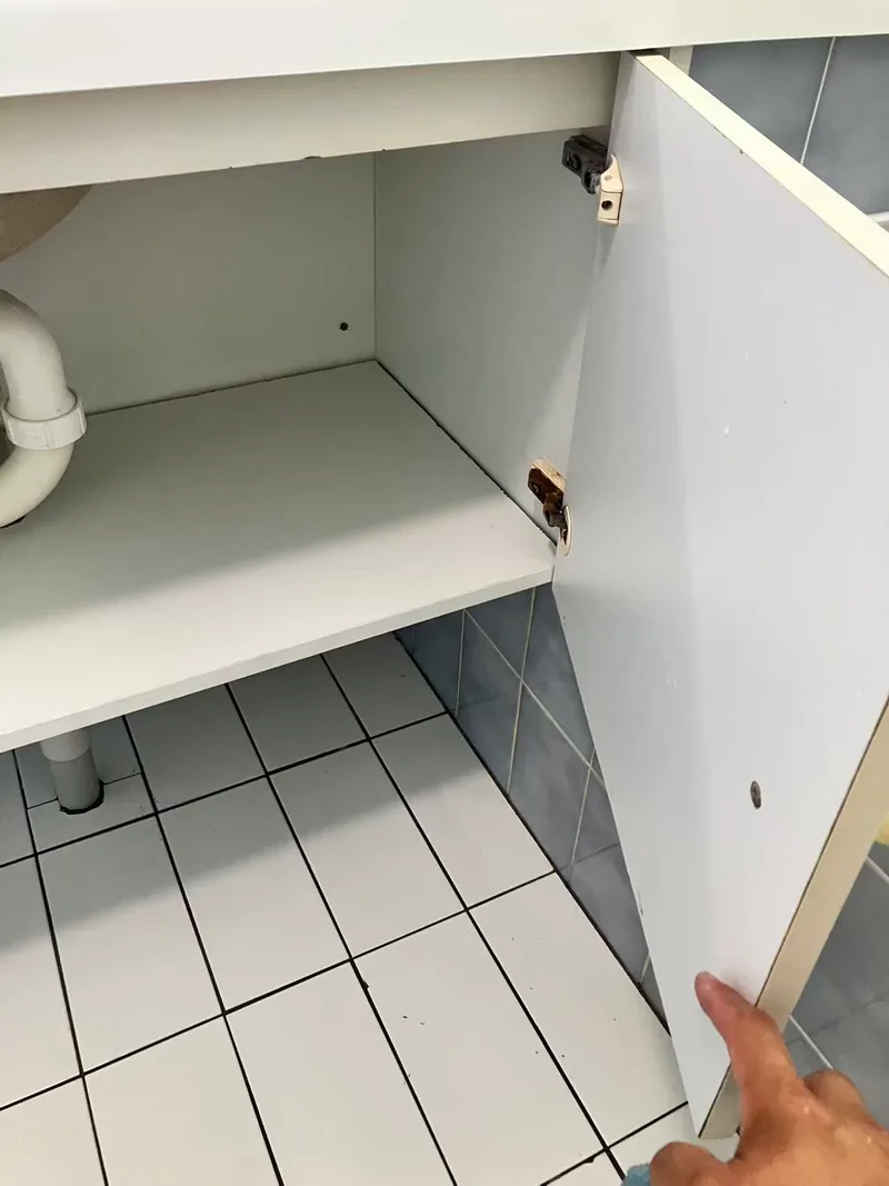 Open vanity cabinet above small square floor tiles